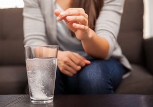 Woman dropping antacid pill into glass of water for acid reflux