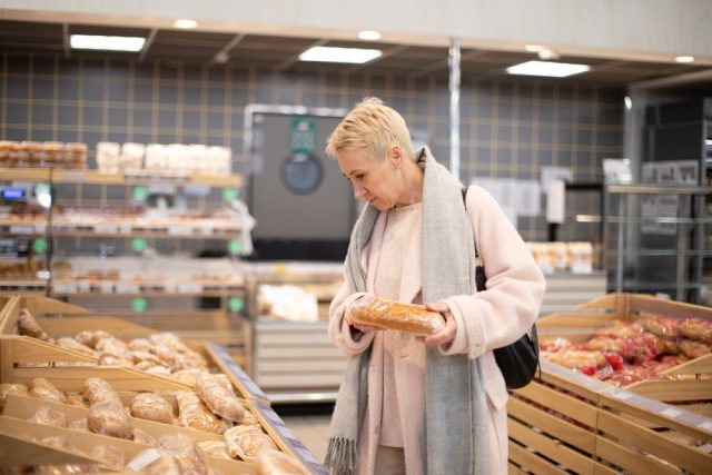 Smiling,Senior,Mature,Woman,Choosing,Bread,And,Baking,In,Grocery